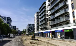 Budowa osiedla, gdzie można sprawdzić, ile zarabia deweloper na bliźniaku. W tle nowoczesne bloki, na pierwszym planie plac budowy.