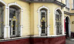 Żółty budynek z ozdobnymi kratami okiennymi. Ile lat musi mieć budynek żeby był zabytkiem? Ten z pewnością ma już swoje lata.