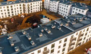 Budowa osiedla mieszkanie plus w trakcie. Nowe bloki z balkonami, plac budowy z koparką i materiałami.