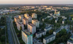 Widok z lotu ptaka na osiedle bloków mieszkalnych i drogę z samochodami o zachodzie słońca.