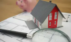 Model domu, świnka skarbonka i lupa na planach. Zastanawiasz się, czy odstępne płaci się co miesiąc?
