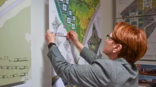 Kobieta analizuje plany osiedla, zastanawiając się, jak zostać radnym osiedla i wpływać na jego rozwój.