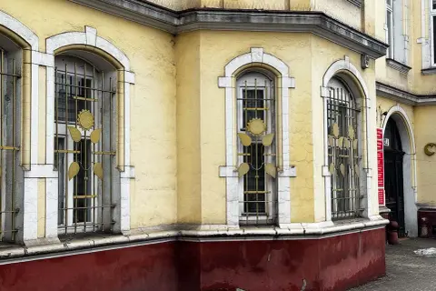 Żółty budynek z ozdobnymi kratami okiennymi. Ile lat musi mieć budynek żeby był zabytkiem? Ten z pewnością ma już swoje lata.