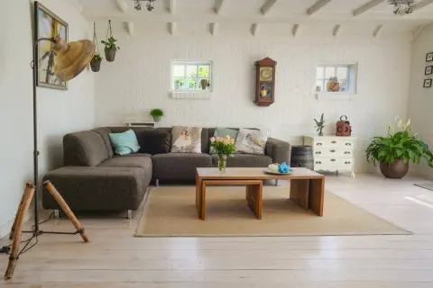 Przytulny salon z ceglaną ścianą, kanapą i stolikiem. Zwróć uwagę na detale, by wiedzieć, na co zwrócić uwagę przy kupnie mieszkania.