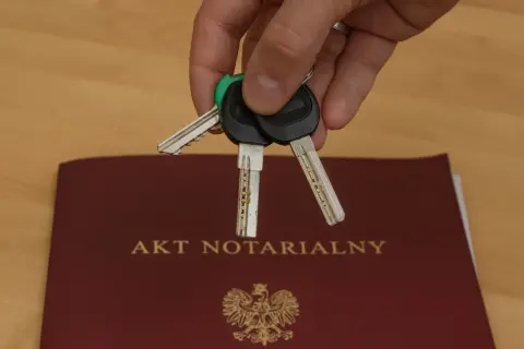 Klucze do nowego domu leżą na akcie notarialnym, symbolizującym własność.