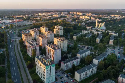 Widok z lotu ptaka na osiedle bloków mieszkalnych i drogę z samochodami o zachodzie słońca.