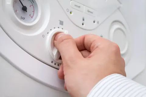 Dłoń kręci pokrętłem termostatu, szukając odpowiedzi, dlaczego nie ma ciepłej wody w kranie.