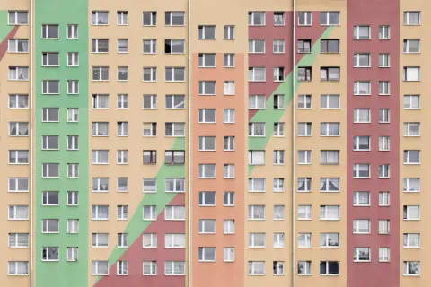 Kolorowy blok mieszkalny z wieloma oknami. Szukasz sposobu, jak przyspieszyć dostanie mieszkania komunalnego?