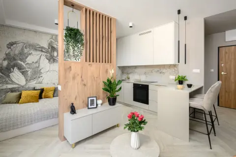 Nowoczesna kawalerka z aneksem kuchennym, łóżkiem i designerską ścianką działową. Idealne rozwiązanie dla singla.