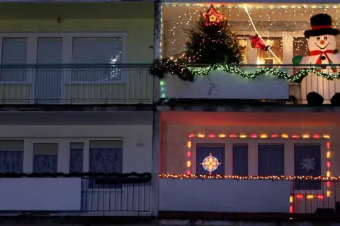 Świąteczne dekoracje na balkonach: choinka, bałwan, Mikołaj i lampki. Pomysł, jak zawiesić lampki na balkonie, by stworzyć magiczny klimat.