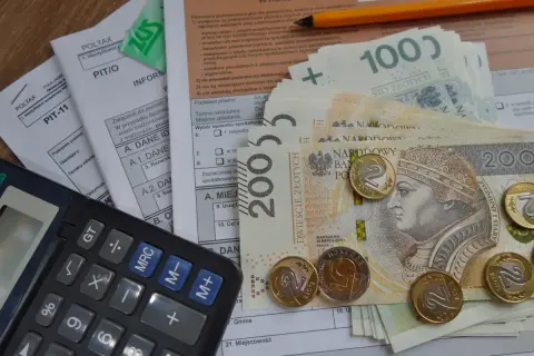 Kalkulator, polskie banknoty i monety na dokumentach podatkowych. Dowiedz się, jak odliczyć kredyt hipoteczny od podatku.