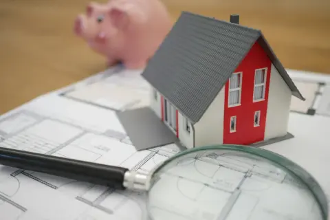 Model domu, świnka skarbonka i lupa na planach. Zastanawiasz się, czy odstępne płaci się co miesiąc?