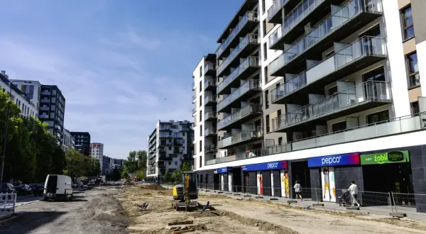 Budowa osiedla, gdzie można sprawdzić, ile zarabia deweloper na bliźniaku. W tle nowoczesne bloki, na pierwszym planie plac budowy.