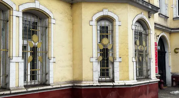 Żółty budynek z ozdobnymi kratami okiennymi. Ile lat musi mieć budynek żeby był zabytkiem? Ten z pewnością ma już swoje lata.
