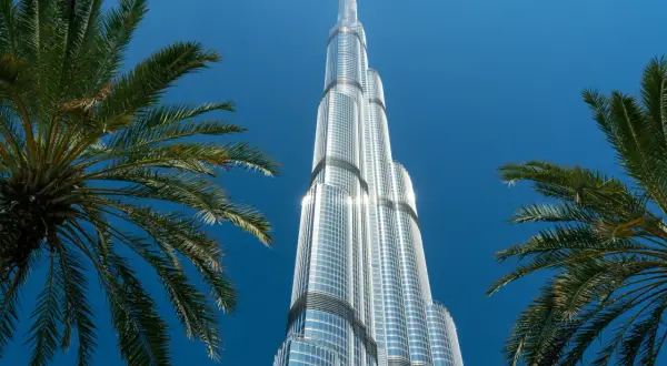 Burj Khalifa, najwyższy budynek świata, ma 163 piętra. Widok zza palm na błękitne niebo.