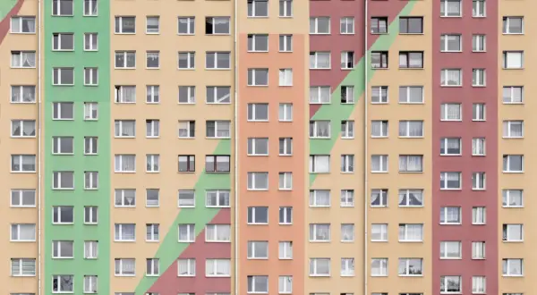Kolorowy blok mieszkalny z wieloma oknami. Szukasz sposobu, jak przyspieszyć dostanie mieszkania komunalnego?