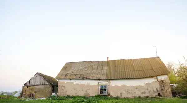 Dwa stare budynki gospodarcze, jeden z kamienia, drugi z tynkiem, wymagają remontu. Zastanawiasz się, jak zalegalizować budynek gospodarczy?