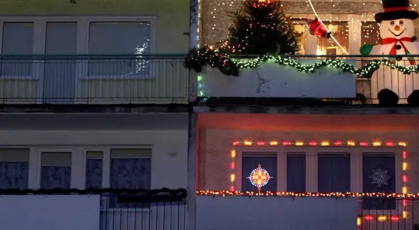 Świąteczne dekoracje na balkonach: choinka, bałwan, Mikołaj i lampki. Pomysł, jak zawiesić lampki na balkonie, by stworzyć magiczny klimat.