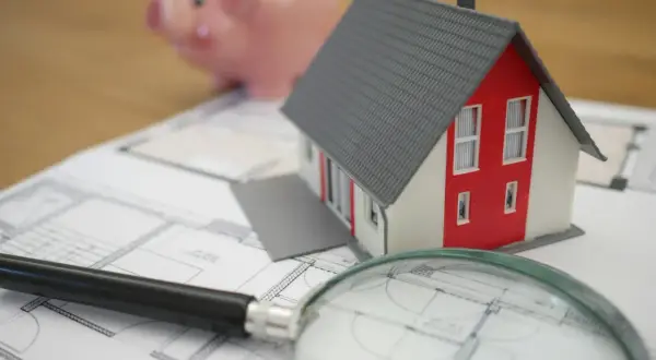 Model domu, świnka skarbonka i lupa na planach. Zastanawiasz się, czy odstępne płaci się co miesiąc?