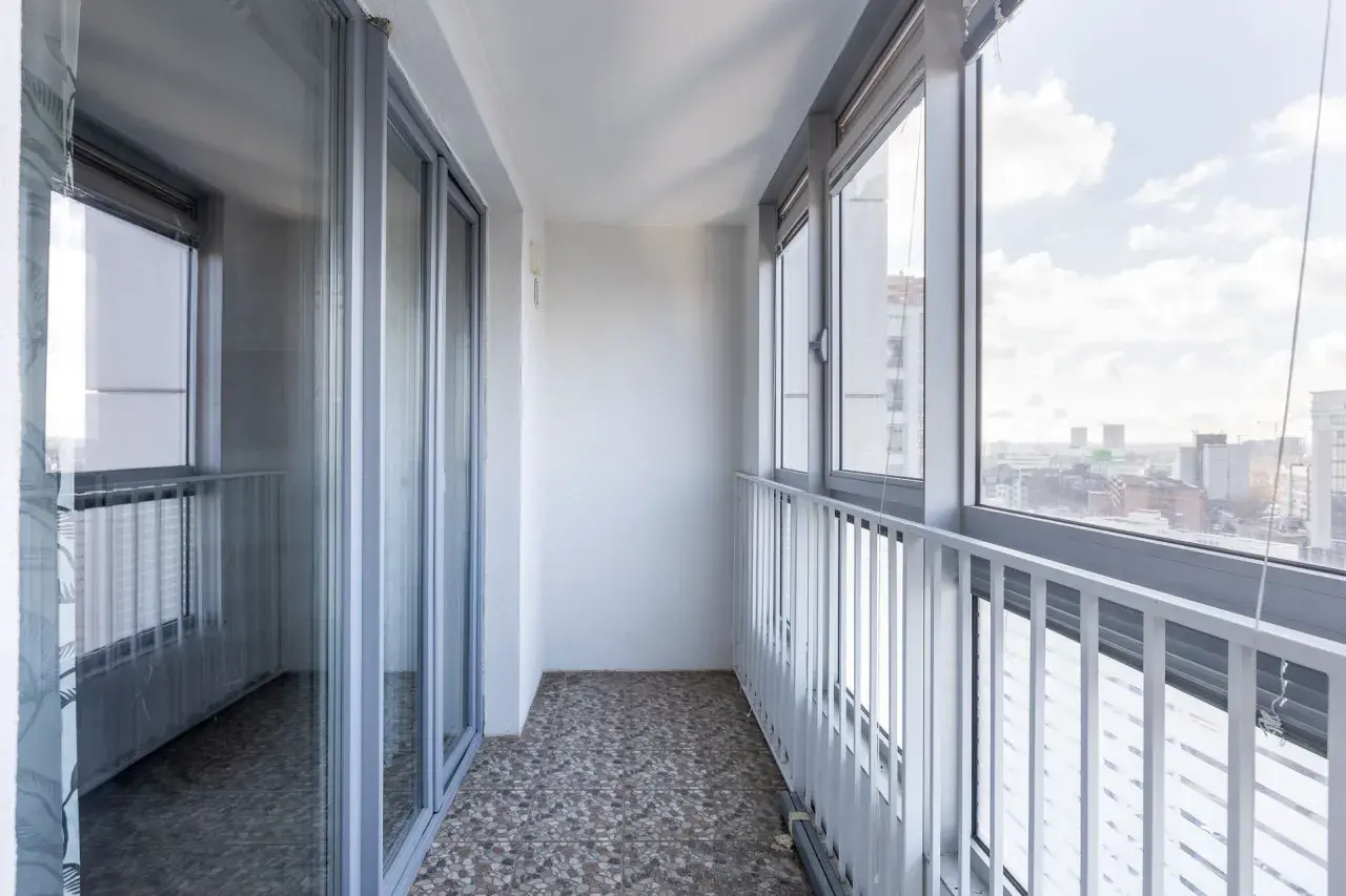Przykładowe wnętrze balkonu, które może posłużyć jako inspiracja, jak zabudować balkon w bloku. Widoczne przeszklone drzwi i okna.