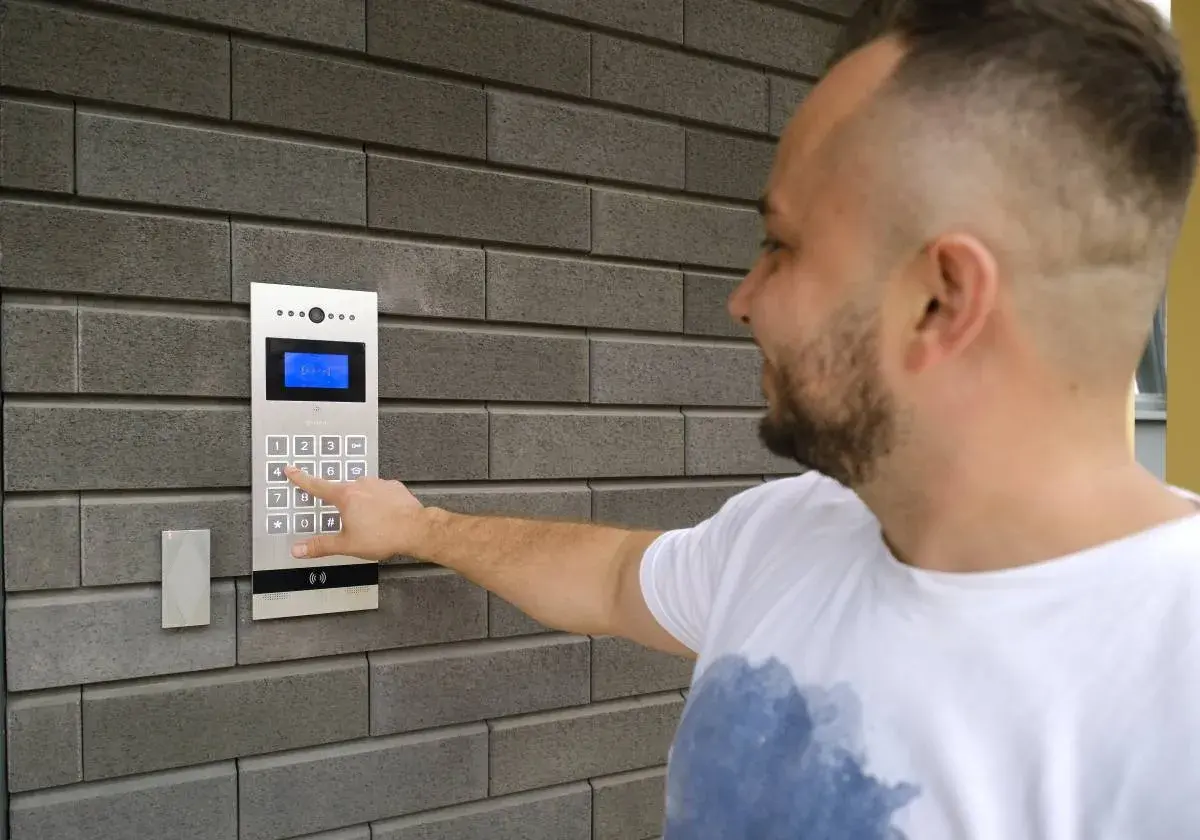 Mężczyzna naciska cyfrę na domofonie, pokazując, jak działa domofon w bloku.