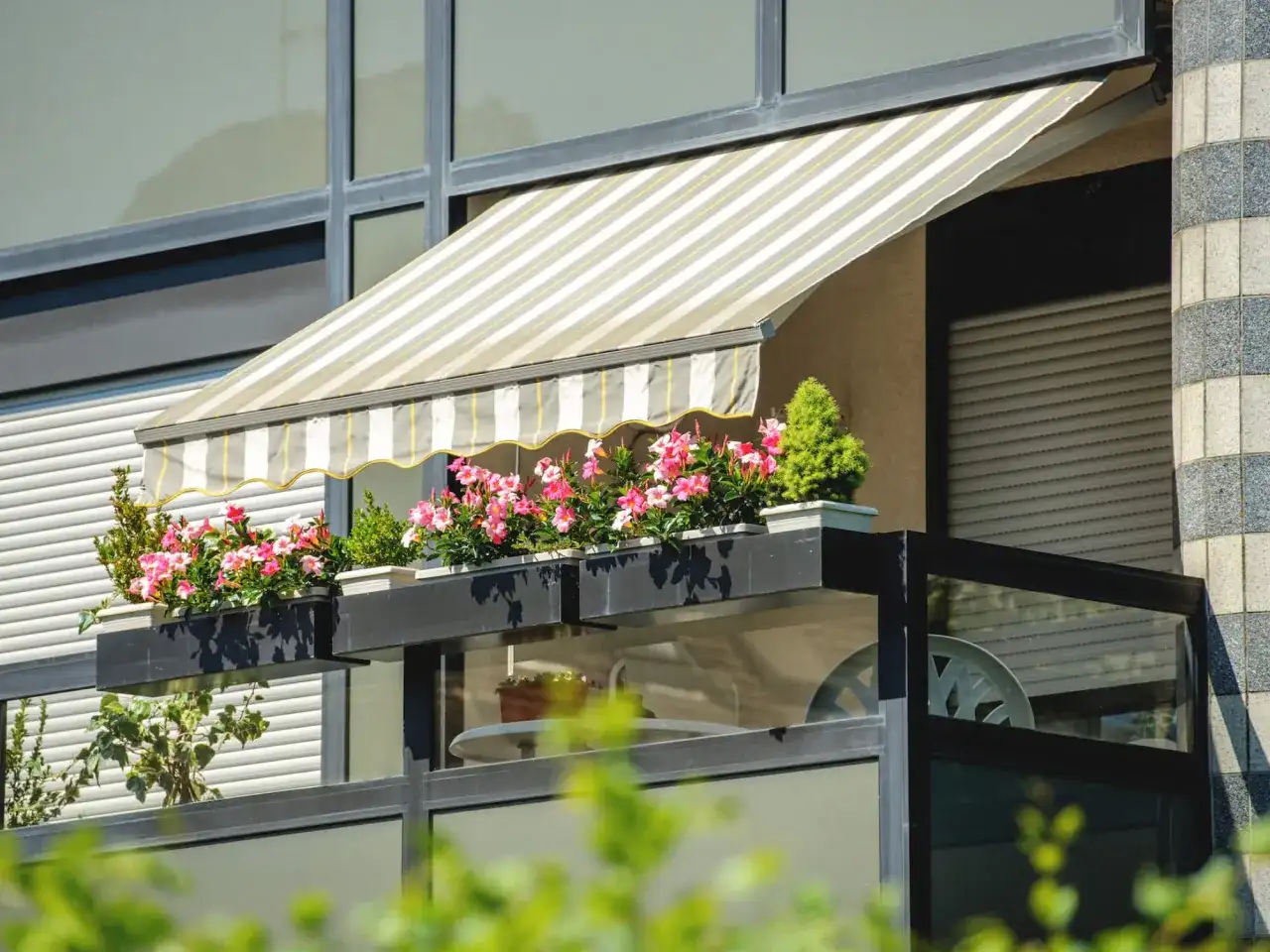 Pnąca się po balustradzie z kwiatami, markiza to świetny sposób, jak osłonić balkon w bloku przed słońcem.