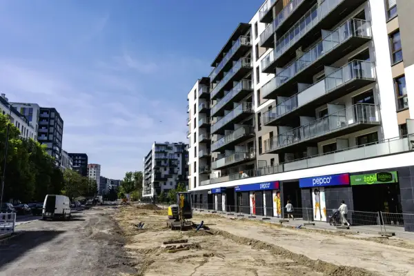 Budowa osiedla, gdzie można sprawdzić, ile zarabia deweloper na bliźniaku. W tle nowoczesne bloki, na pierwszym planie plac budowy.