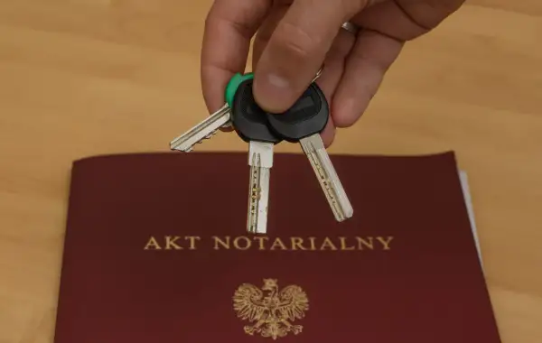 Klucze do nowego domu leżą na akcie notarialnym, symbolizującym własność.