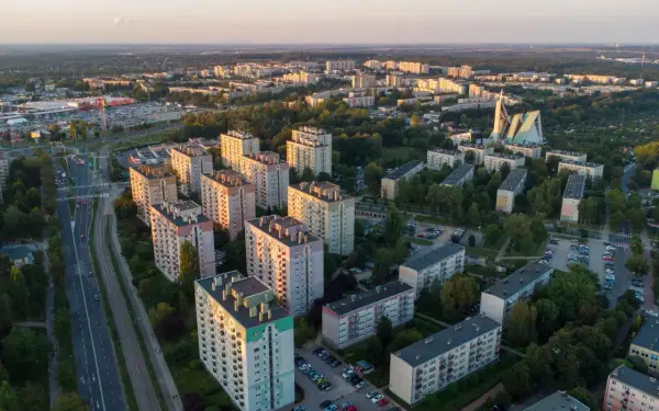 Widok z lotu ptaka na osiedle bloków mieszkalnych i drogę z samochodami o zachodzie słońca.